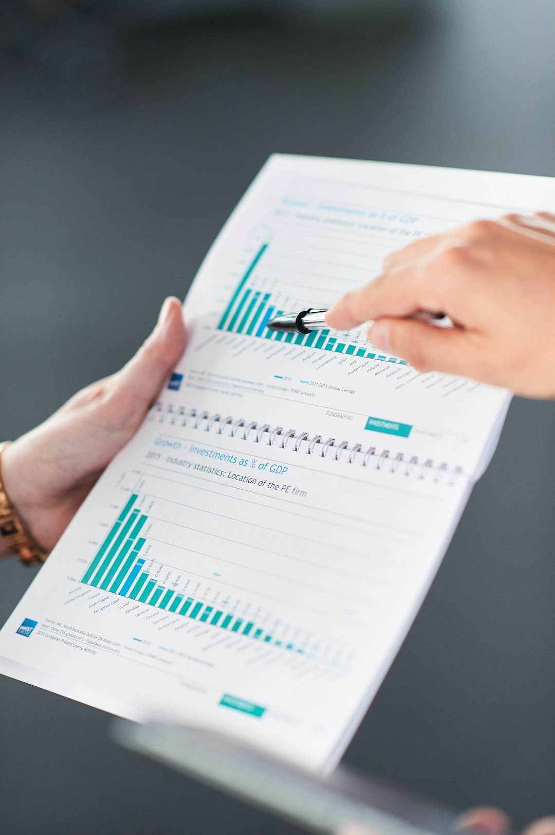 Hands writing market analysis notes beside printed charts